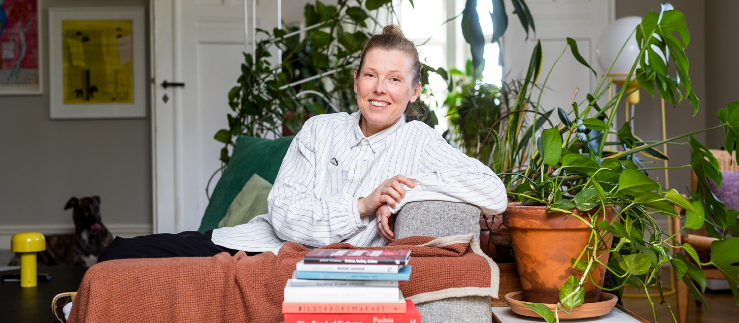 Designer Louise Hederström i sin ateljé, omgiven av växter och böcker.
