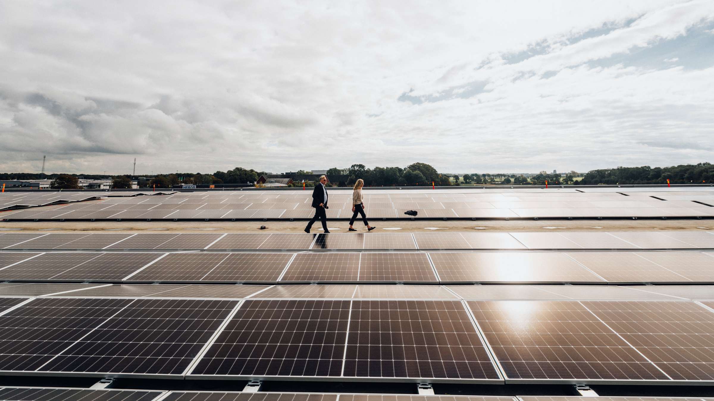 Två personer går på ett tak med solceller.