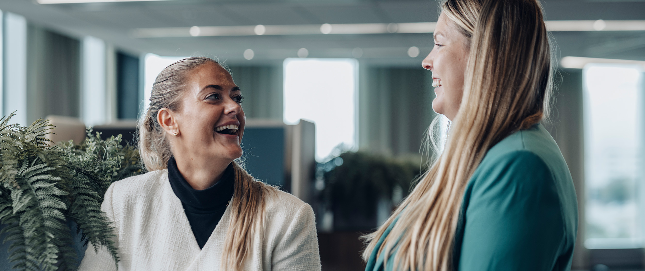 En kvinnlig HR-manager och en  kvinnlig operations manager ler tillsammans.